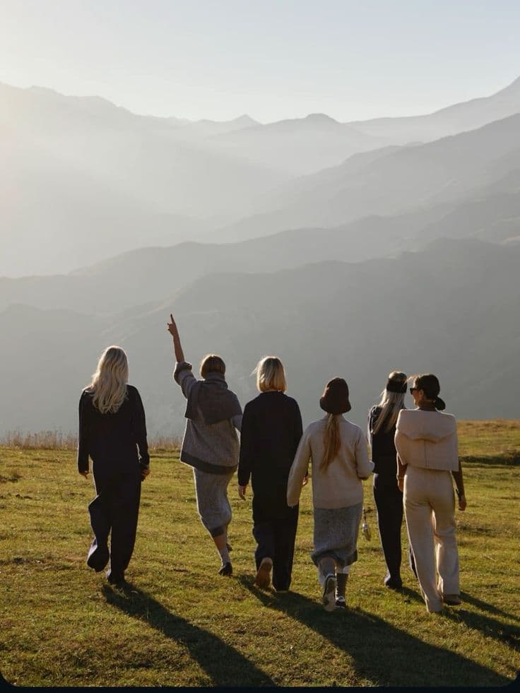 Group of women walking together through a mountain landscape at golden hour