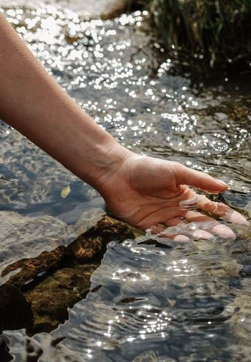 Hand gently touching sparkling water — connection with nature and renewal