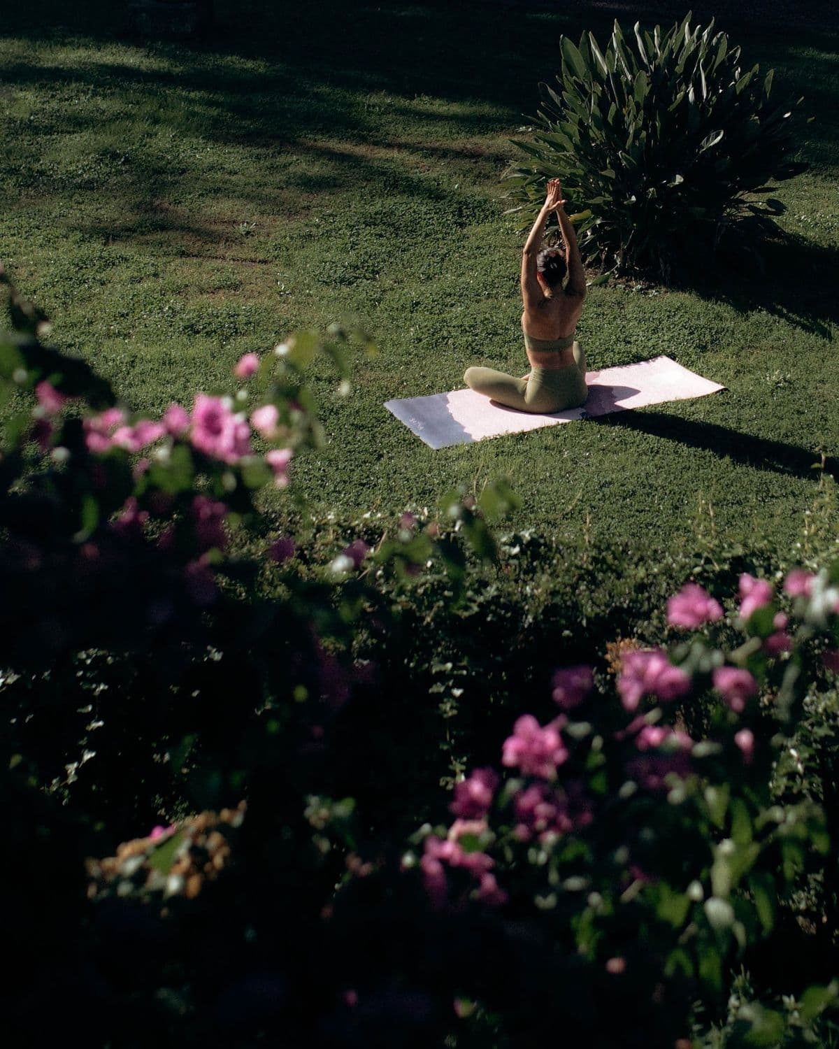 Person practicing yoga outdoors surrounded by flowers — movement and serenity